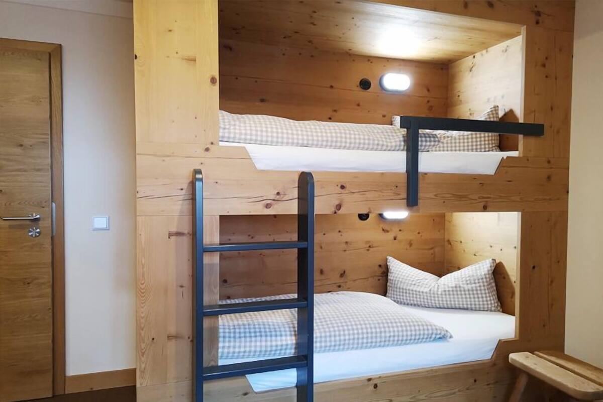 Habitación con literas, escalera, paredes de madera y una puerta.