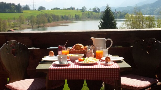 Una mesa lista para el desayuno con una vista panorámica de un lago y colinas.