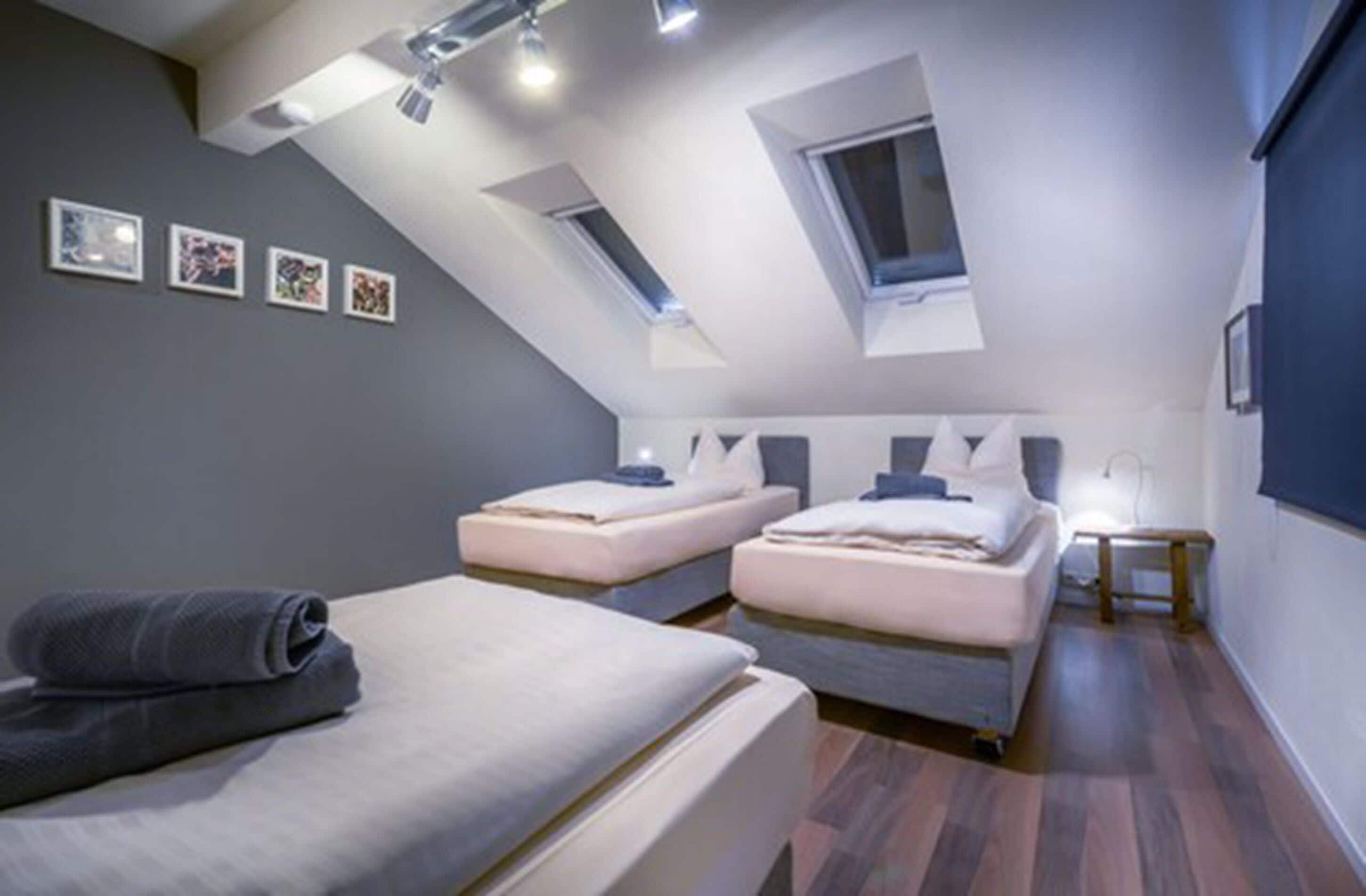 Ein modernes Schlafzimmer mit zwei Betten, einem Oberlicht und einem kleinen Nachttisch.