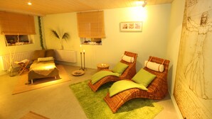Una habitación acogedora con una cama, dos sillones, una mesita y una pared decorada con obras de arte.