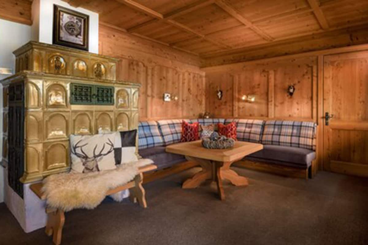 Interior de una cabaña de madera con un sofá, una mesa y un banco cubierto de piel.