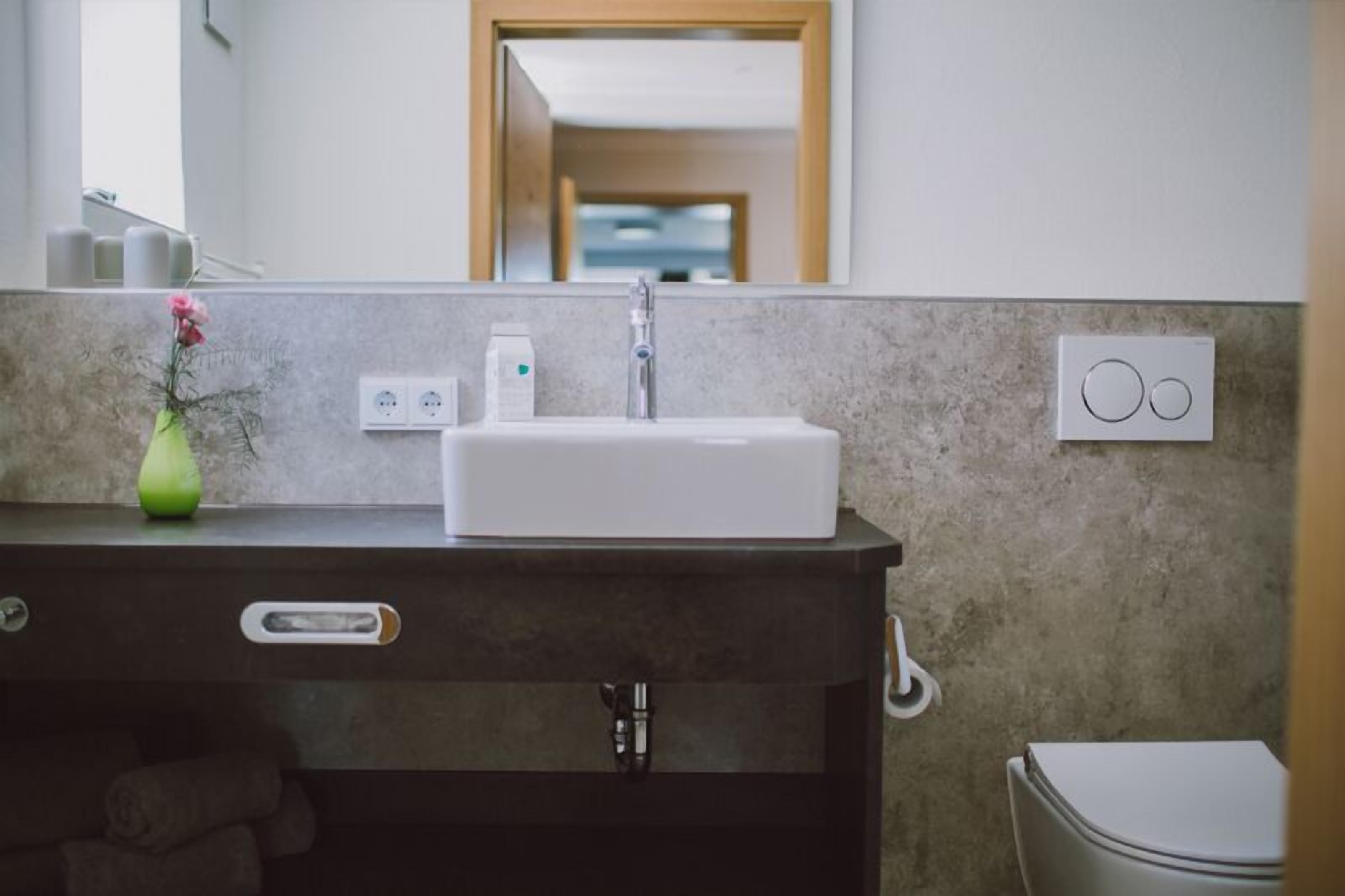 A bathroom with a white sink, a mirror, a towel rack, and a toilet.