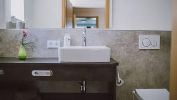 A bathroom with a white sink, a mirror, a towel rack, and a toilet.