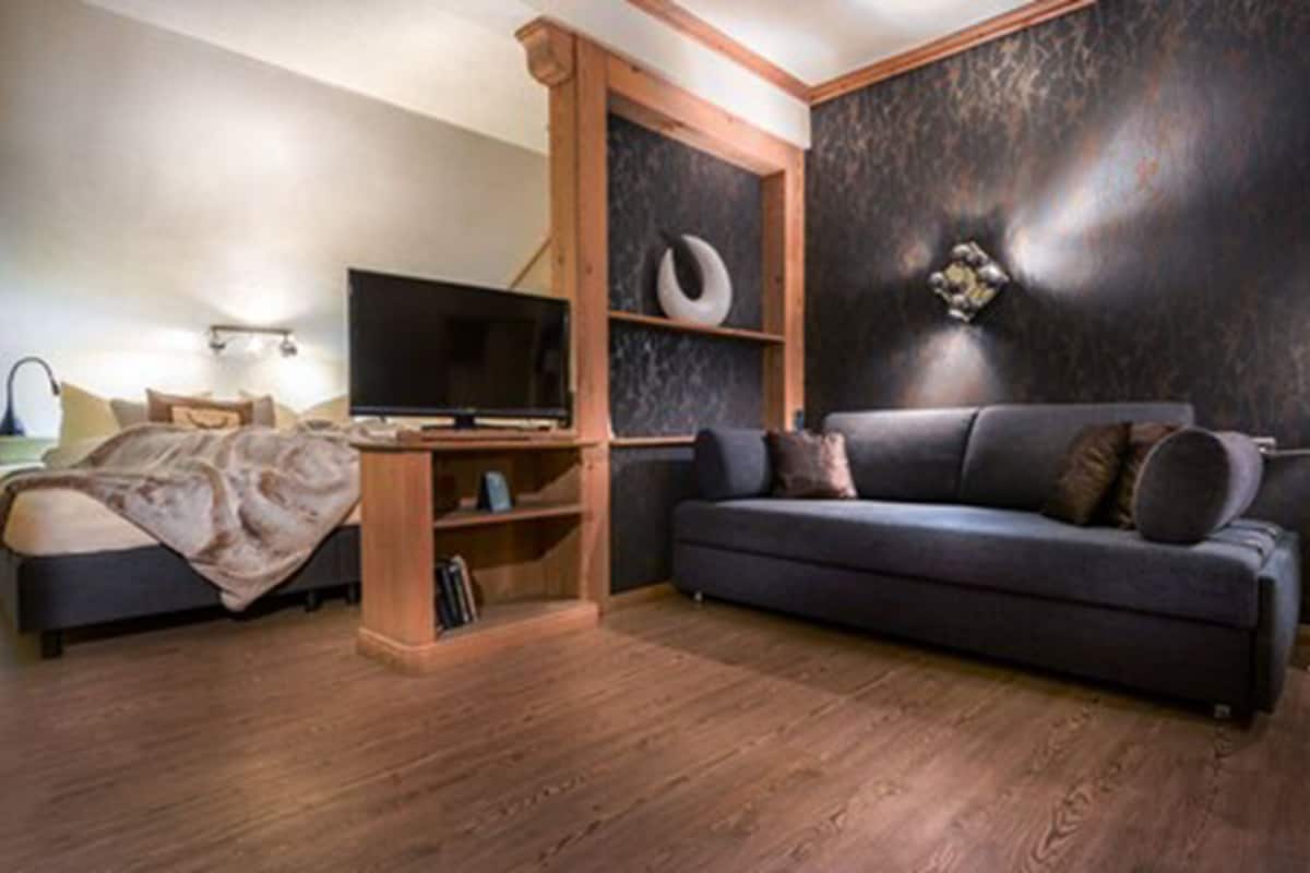 Un dormitorio moderno con cama, televisor, sofá y escritorio.