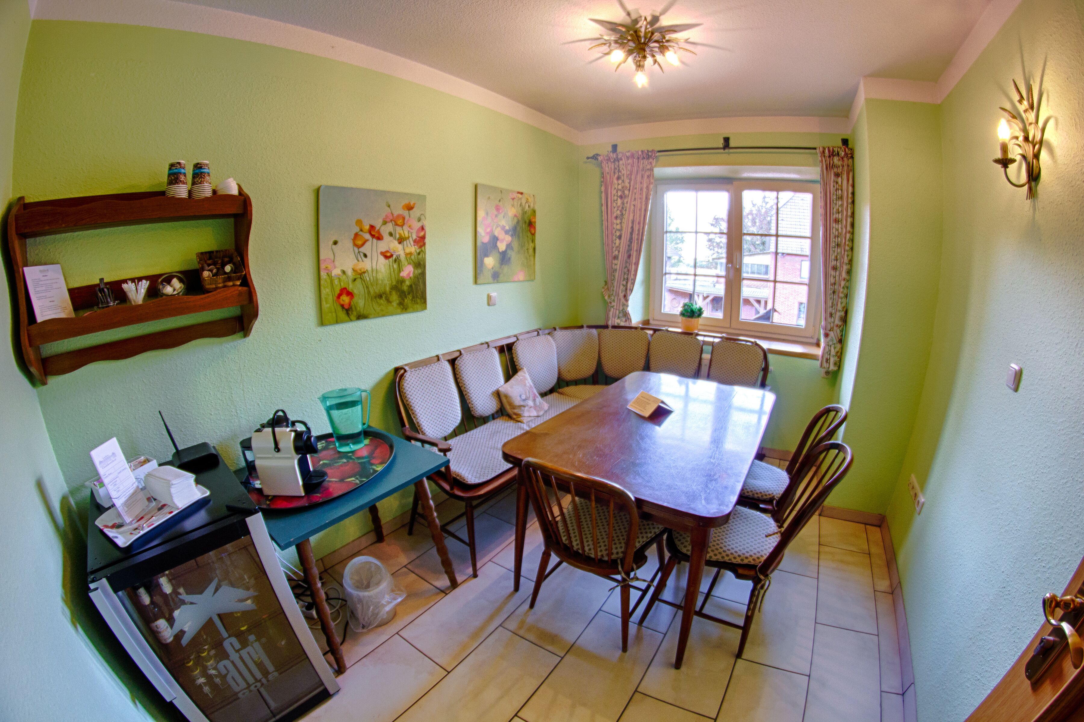 Uma área de refeições com uma mesa de madeira, cadeiras, um banco e uma janela com cortinas.