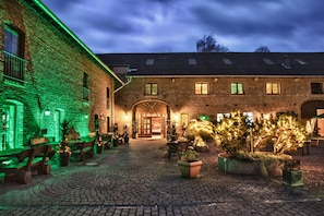 A courtyard with brick buildings, outdoor seating, and potted plants. - Landhaus Göddertzhof (Erkelenz)