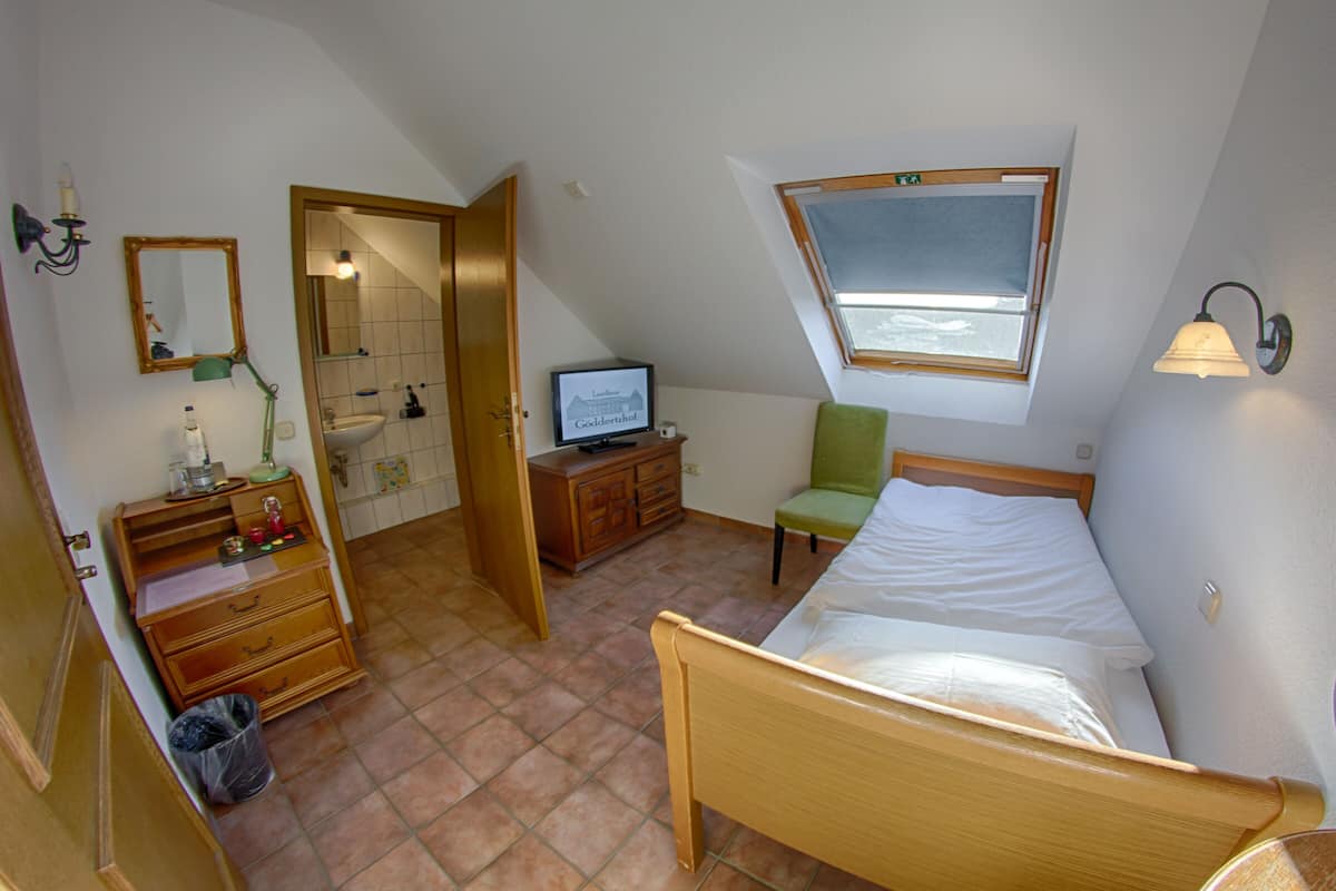 Un dormitorio con cama, televisor, silla, cómoda y ventana.