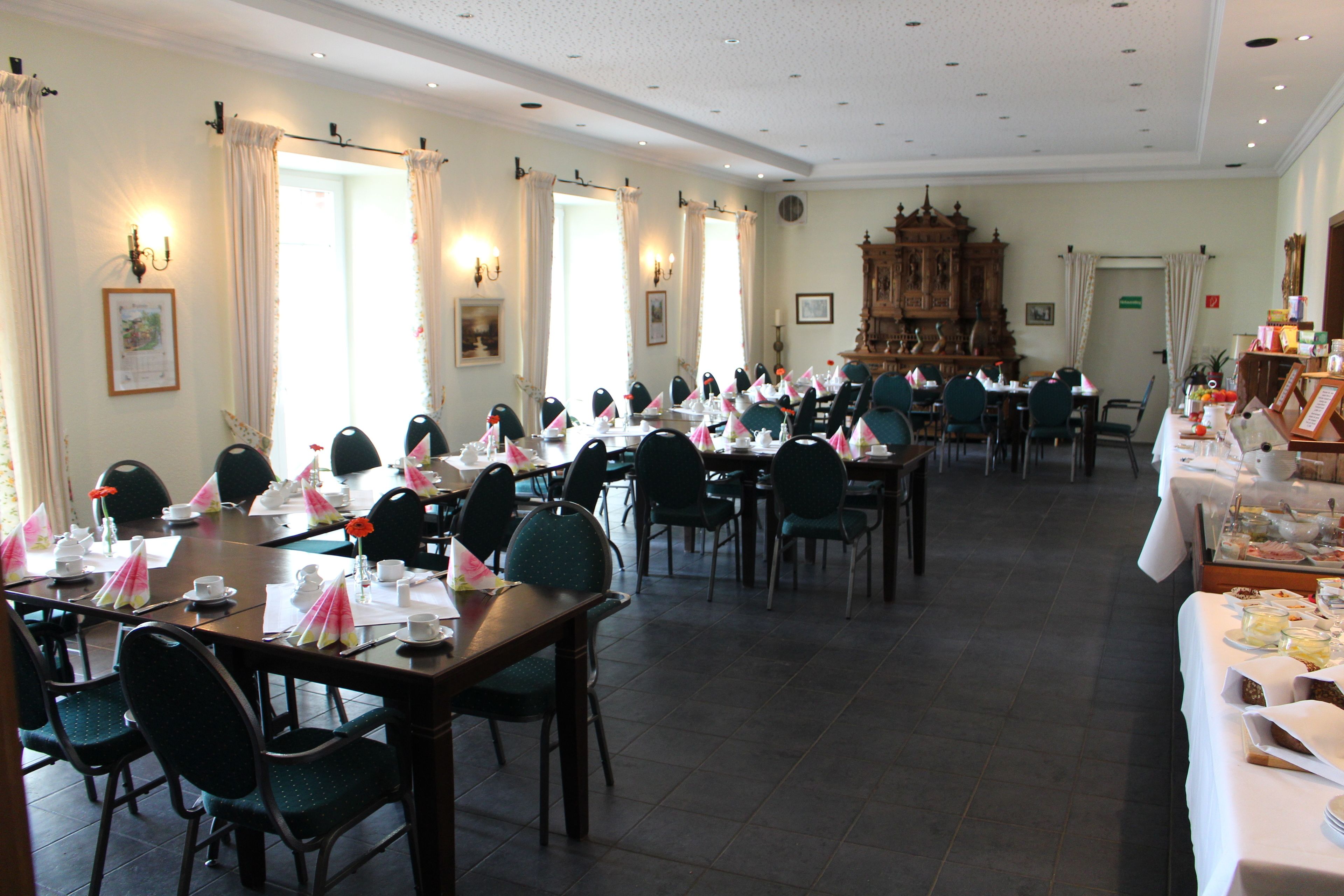 Un comedor formal con varias mesas dispuestas para una comida, sillas alrededor de cada una y un gran aparador de madera al fondo.