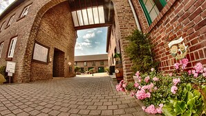 Un edificio de ladrillo con una amplia entrada en arco, un cartel de bienvenida y un patio empedrado.