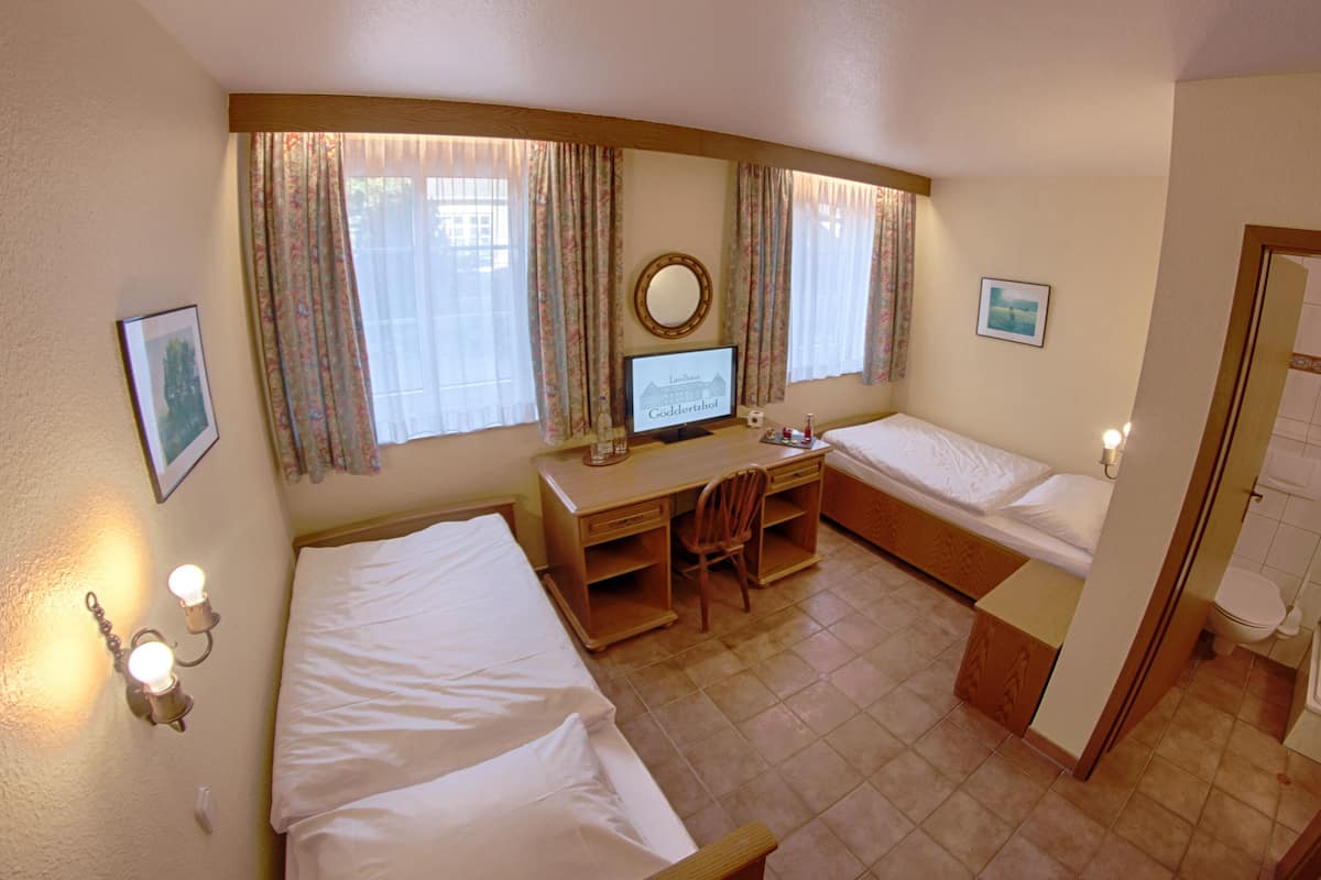 Una habitación de hotel con dos camas, un escritorio, un ordenador y un baño.