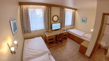 A hotel room with two beds, a desk, a computer, and a bathroom.