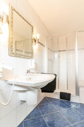 Enjoy a refreshing shower in this bathroom featuring a glass-enclosed shower, sink, and large mirror.