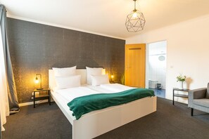 Relax in a spacious room with a large bed, bedside tables, and a comfortable armchair.