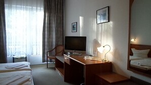 A hotel room with a bed, a desk with a television, a chair, and a lamp. - Hotel Schützenhaus (Bad Dueben)