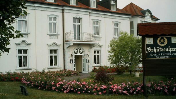 A large, white building with a balcony and a sign for 'Schützenhaus Hotel & Restaurant Biergarten'. - Hotel Schützenhaus (Bad Dueben)