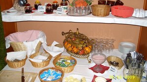 A buffet table with various food items, including a fruit display, baskets of bread, and a selection of cheeses. - Hotel Schützenhaus (Bad Dueben)