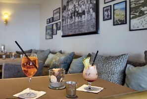 A table with two cocktails and a small bowl of nuts.