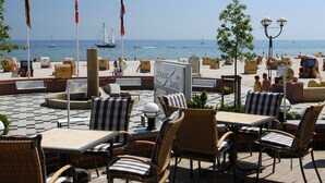 An outdoor seating area with tables and chairs, a signboard, and flags. - Hotel Strandidyll (Groemitz)