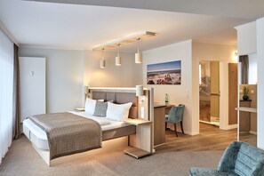 A modern hotel room with a bed, desk, and seating area.