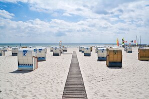 A beach with rows of numbered beach chairs and a lifeguard tower in the background.