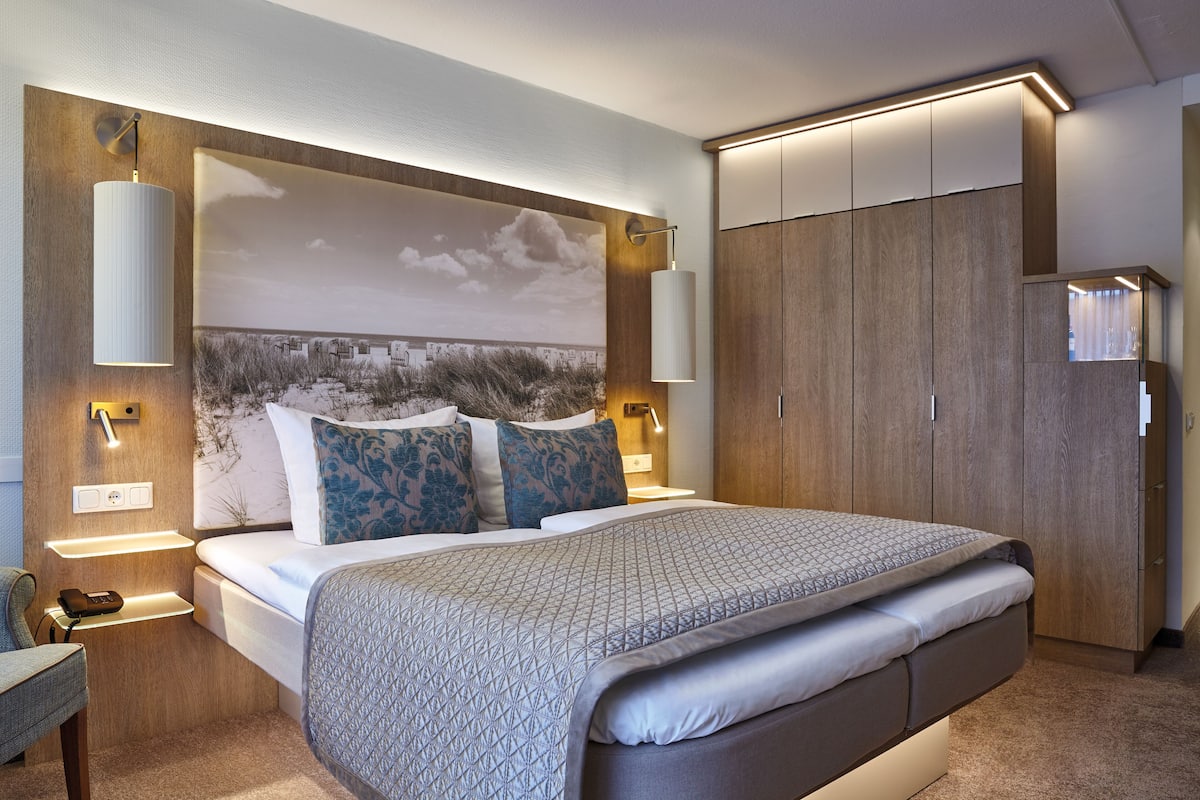 A modern bedroom with a large bed, built-in wardrobe, and wall-mounted lighting.