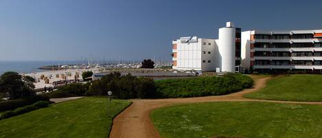 A hotel with a central courtyard, a marina with boats, and a view of the sea.