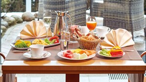 A breakfast table set with plates of food, a pitcher, glasses, and a basket of bread. - Hotel Strandidyll (Groemitz)