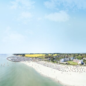 A coastal town with a beach, marina, and residential buildings. - Hotel Strandidyll (Groemitz)