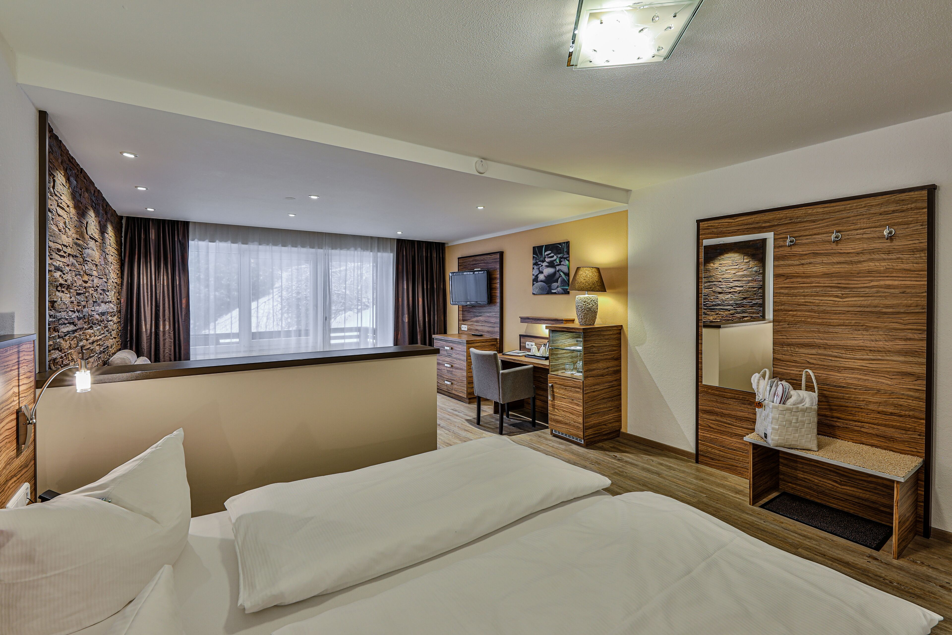 A hotel room with two beds, a desk, a TV, and a wardrobe.