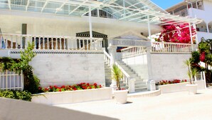A hotel with a white facade, a glass-covered upper level, and a staircase leading to the entrance. - Olympic Kosma Hotel (Kassandra)