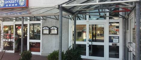 A hotel entrance with a covered walkway, glass doors, and a sign for 'China Restaurant Dynasty'.