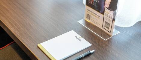 Un bureau en bois avec un bloc-notes, un stylo et un panneau indiquant un code QR.
