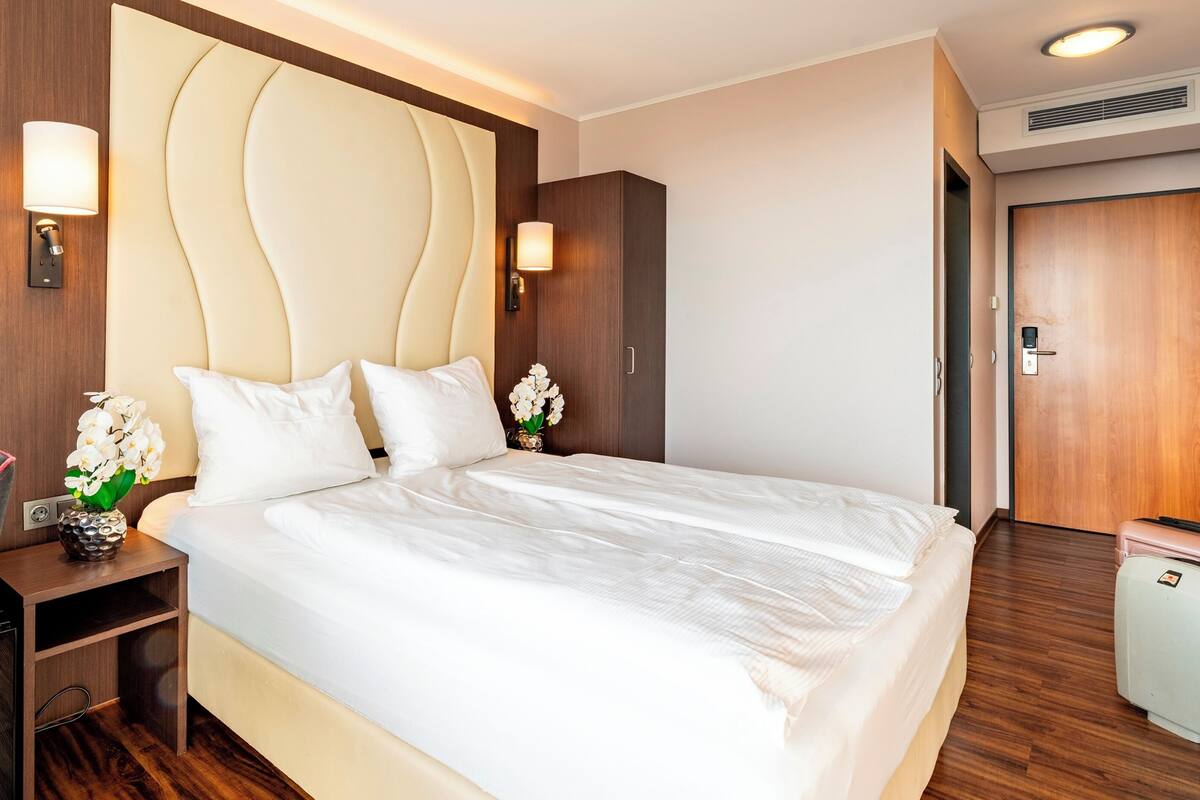 Une chambre d’hôtel avec un grand lit, des tables de chevet, un bureau et une armoire.