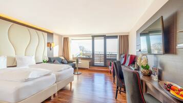 Une chambre d’hôtel avec un grand lit, un canapé, une table à manger avec des chaises, une télévision et un balcon avec vue.