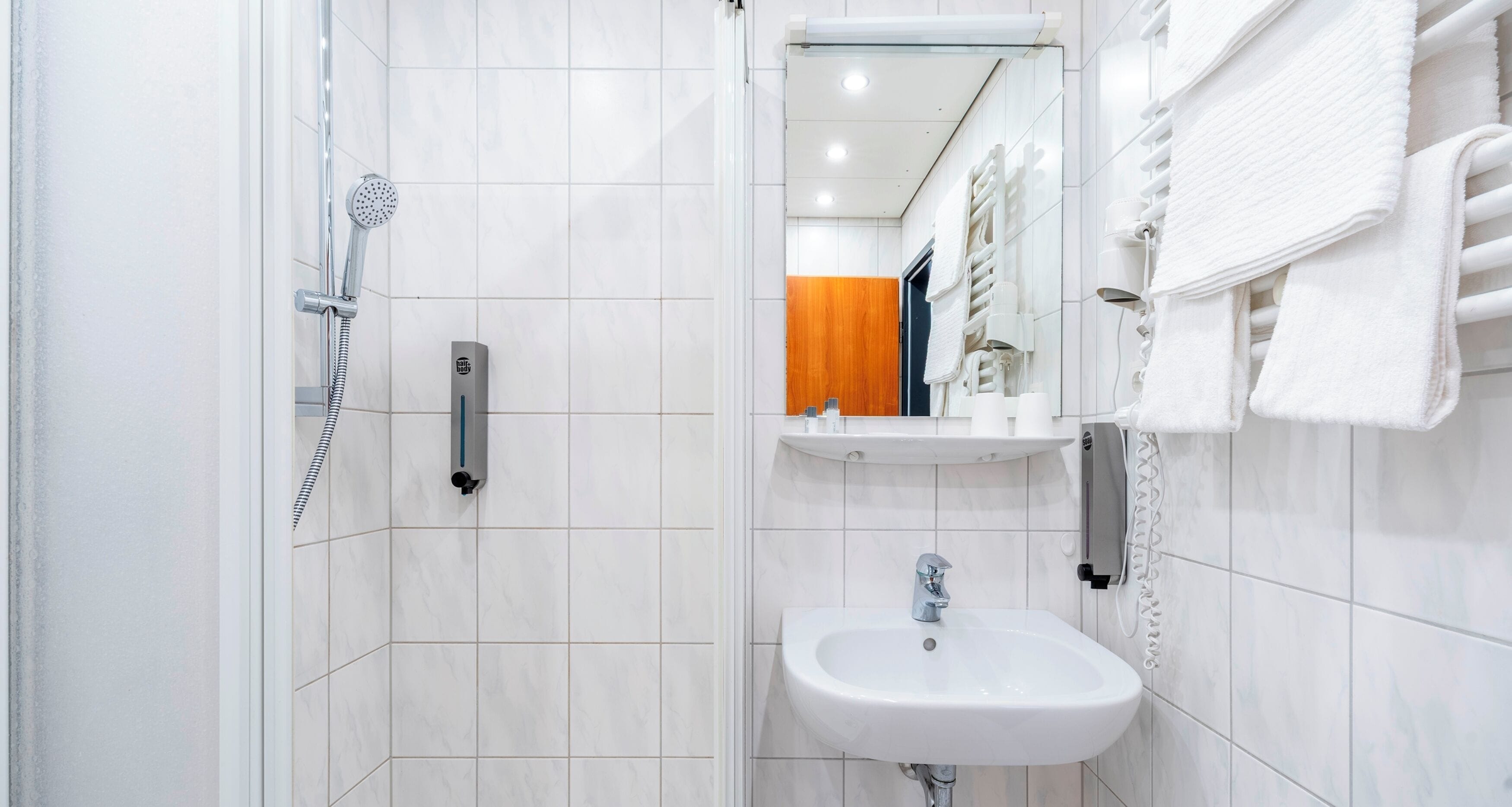 Un baño moderno con ducha, lavabo y toallero.