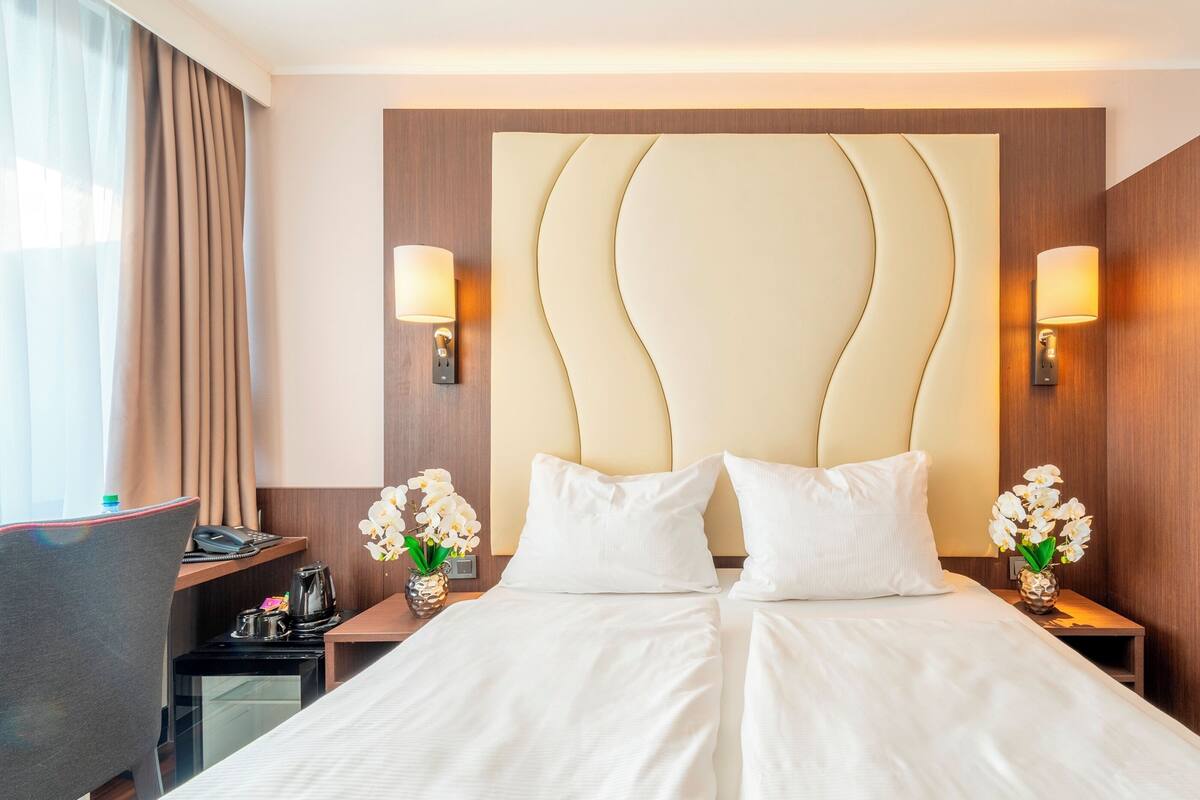 Une chambre d’hôtel avec un grand lit, deux tables de chevet, un bureau et une armoire.
