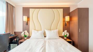 Une chambre d’hôtel avec un grand lit, deux tables de chevet, un bureau et une armoire.