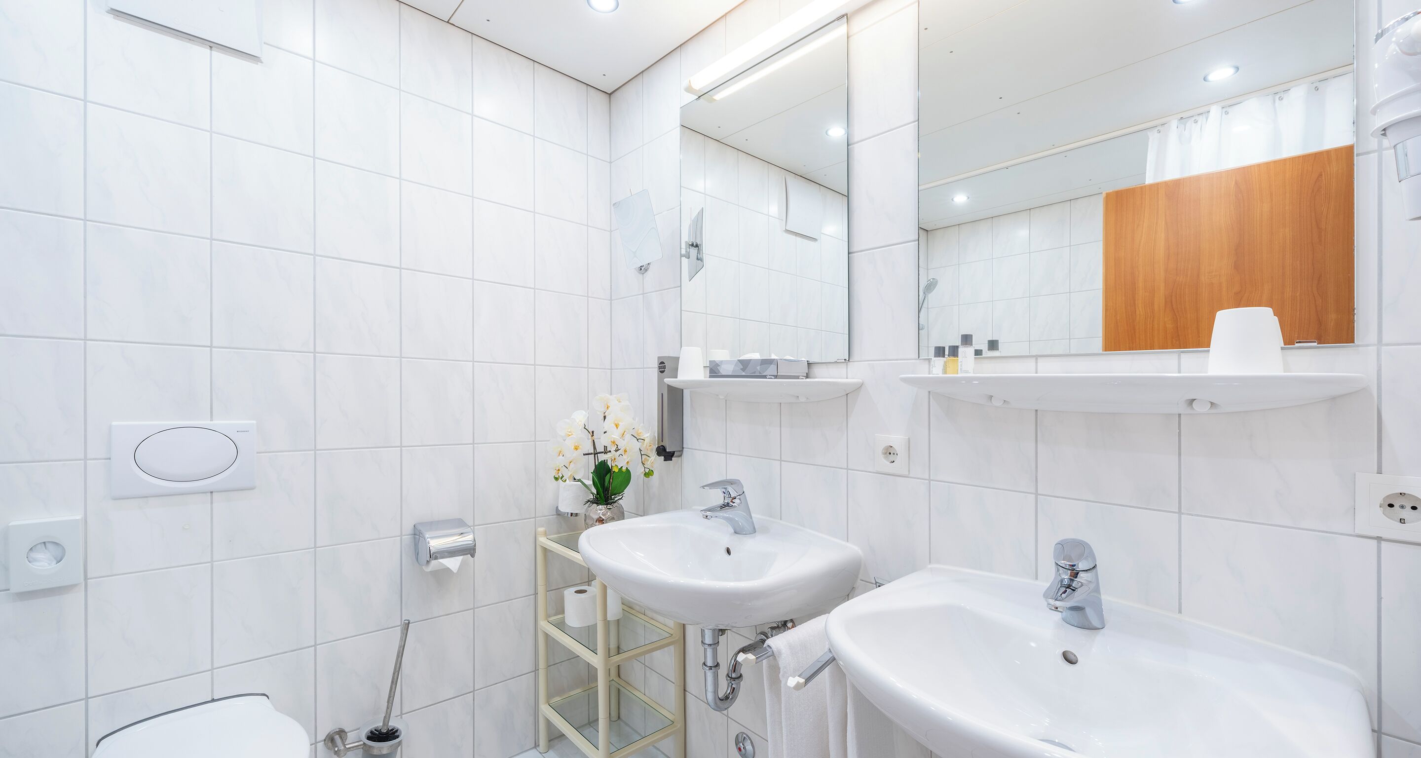 Un baño moderno con dos lavamanos, un inodoro y un espejo.