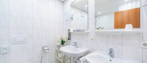 A modern bathroom with two sinks, a toilet, and a mirror.