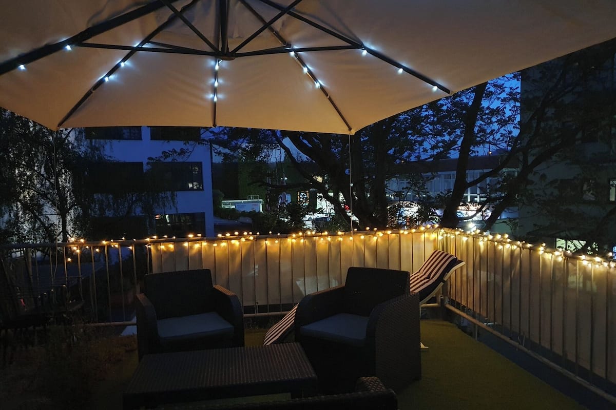 An outdoor patio with a canopy, string lights, and wicker furniture.