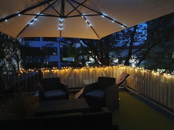 An outdoor patio with a canopy, string lights, and wicker furniture.