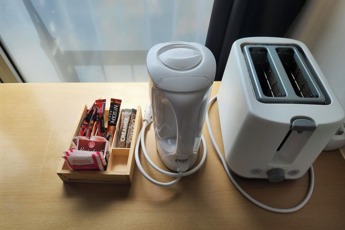 A kitchen counter with a toaster, a white appliance, and a wooden box containing food items.