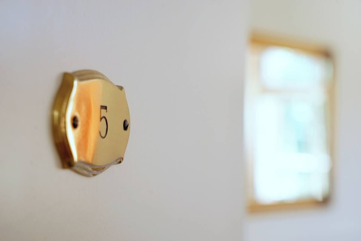 A close-up of a brass doorbell with the number 5, indicating a room or office door.