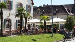 An outdoor café with tables and chairs, surrounded by buildings with distinct architectural features. - Hotel Gasthaus Schützen (Freiburg im Breisgau)