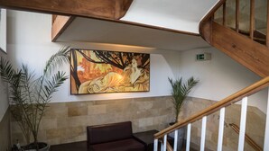 A lobby with a wooden staircase, a bench, a sofa, and a large painting on the wall. - Hotel Gasthaus Schützen (Freiburg im Breisgau)