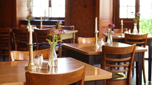 A restaurant interior with wooden tables and chairs, candles, and floral centerpieces. - Hotel Gasthaus Schützen (Freiburg im Breisgau)