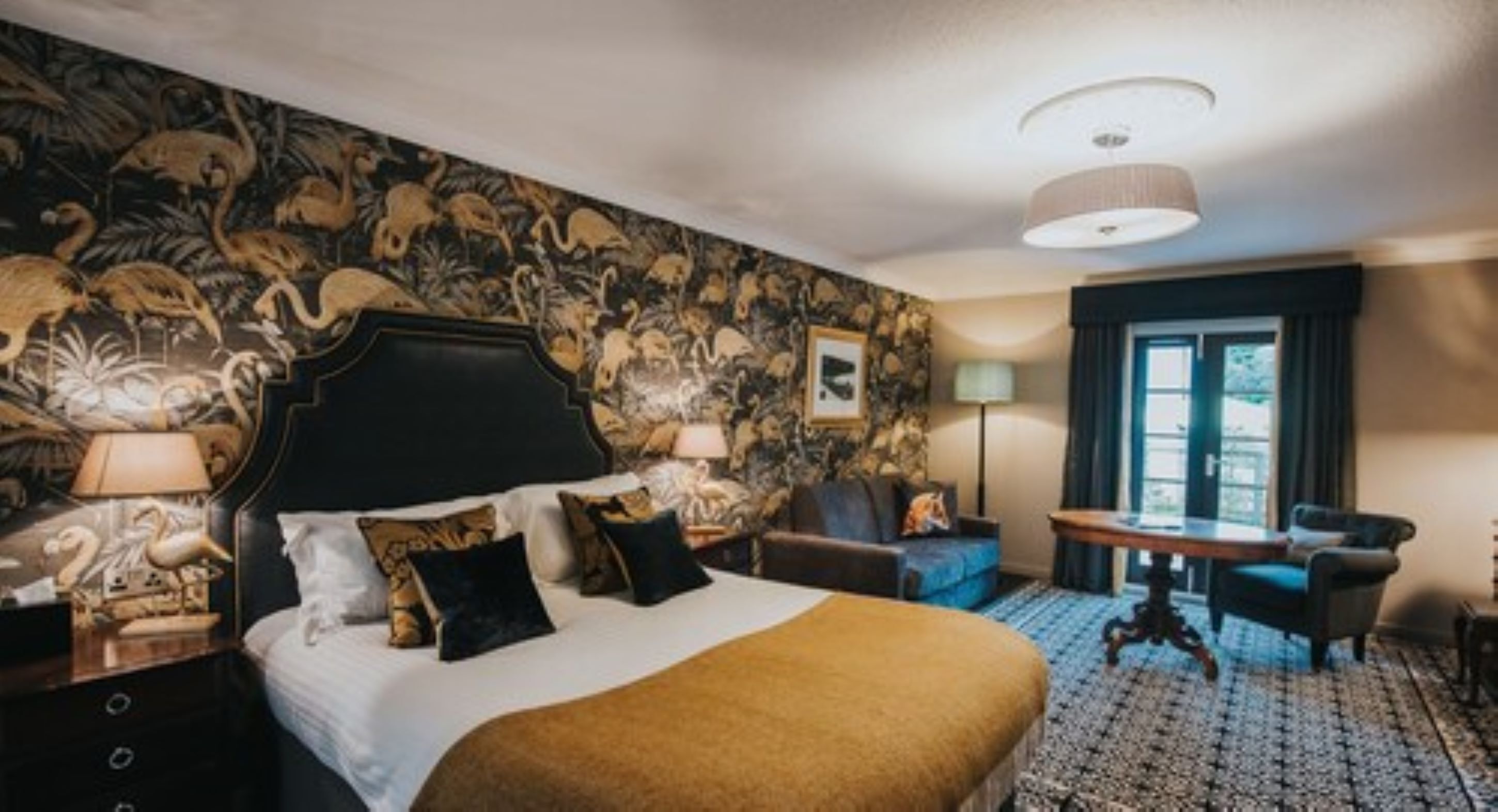 A hotel room with a large bed, a desk, a chair, and a view of the outdoors.