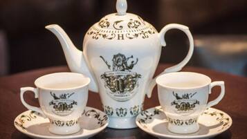 A tea set with a teapot and two cups, each with matching saucers, on a wooden table.