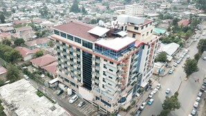 Un hotel de varios pisos con techo rojo, balcones y un estacionamiento.