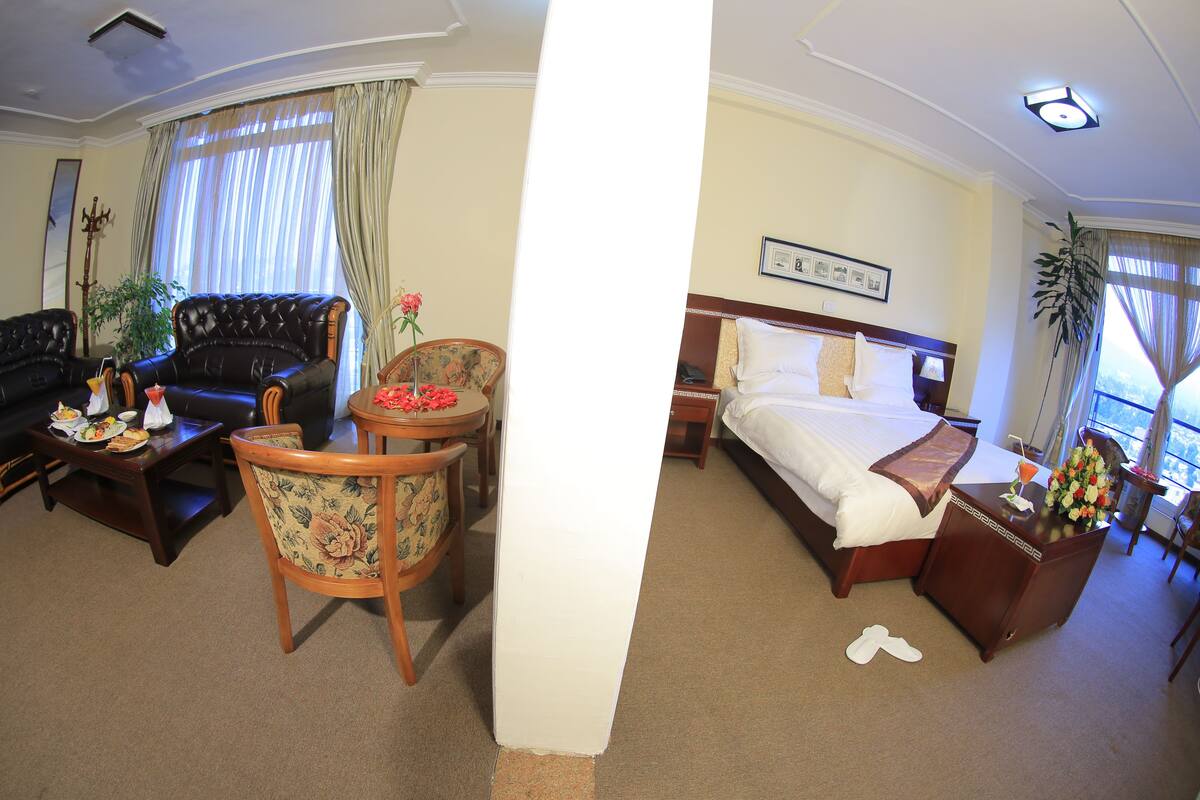 Una habitación de hotel con una cama grande, un sofá, una mesa de comedor y una silla.
